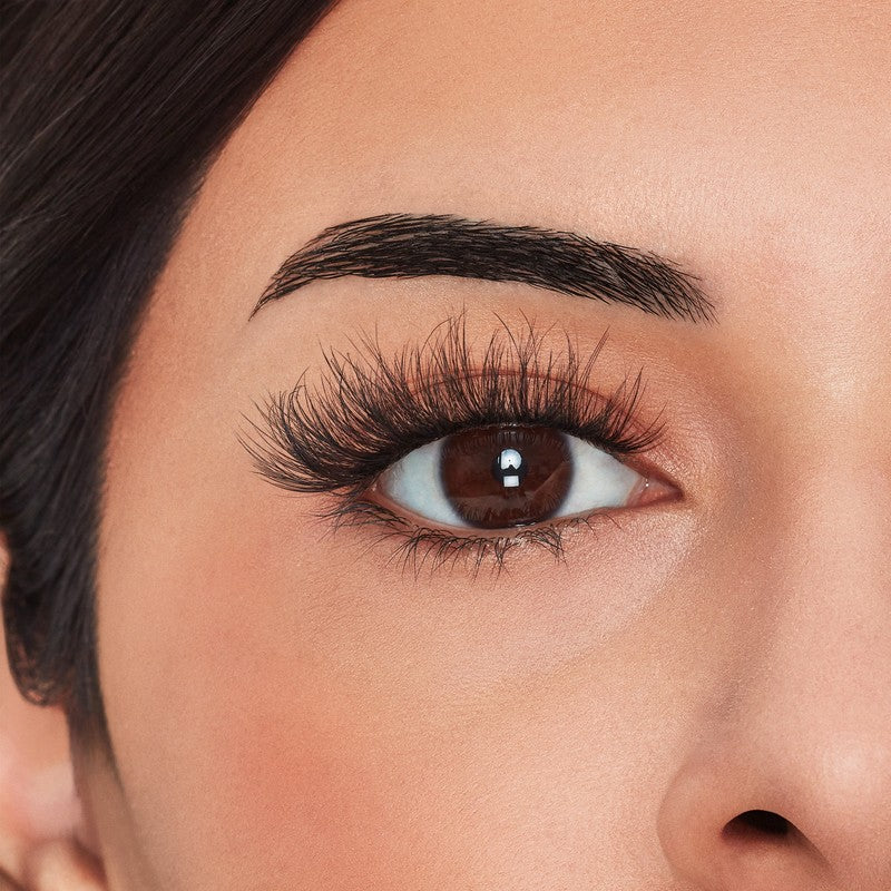 Close-up of a woman's eye with long, dark eyelashes and well-groomed eyebrows.