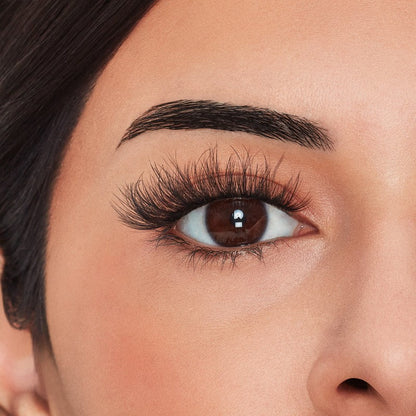Close-up of a woman's eye with long, dark eyelashes and well-groomed eyebrows.