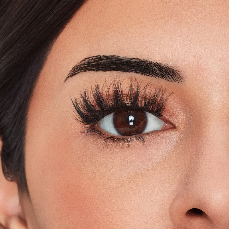 Close-up of a woman's eye with long, dark eyelashes and well-groomed eyebrows.